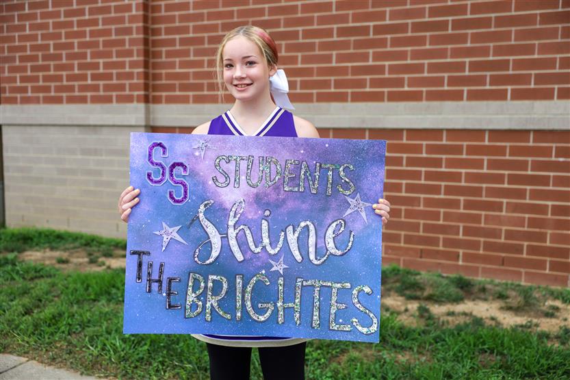 A student poses with a back to school sign